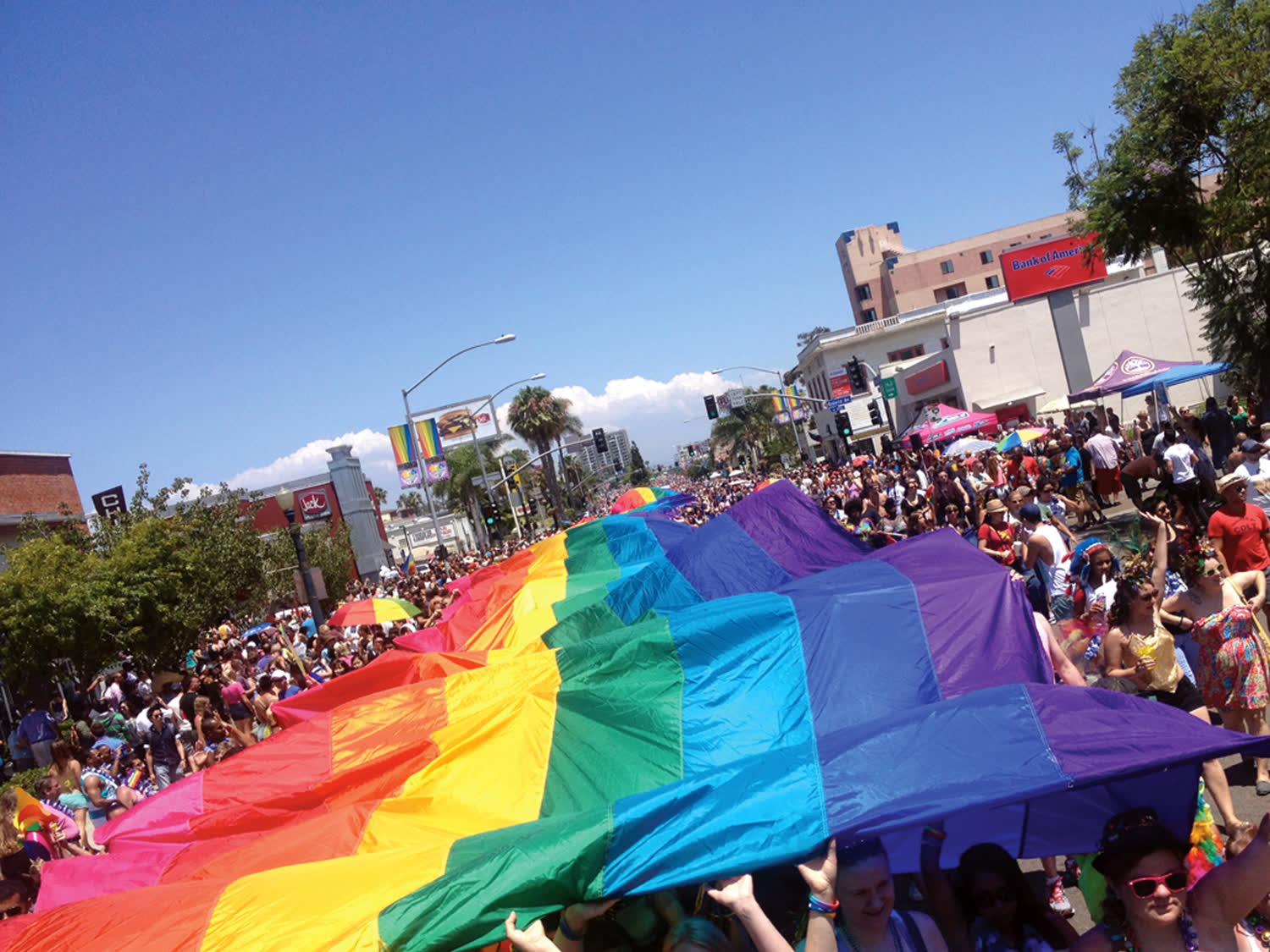 A giant rainbow flag carried down the street during the San Diego Pride parade