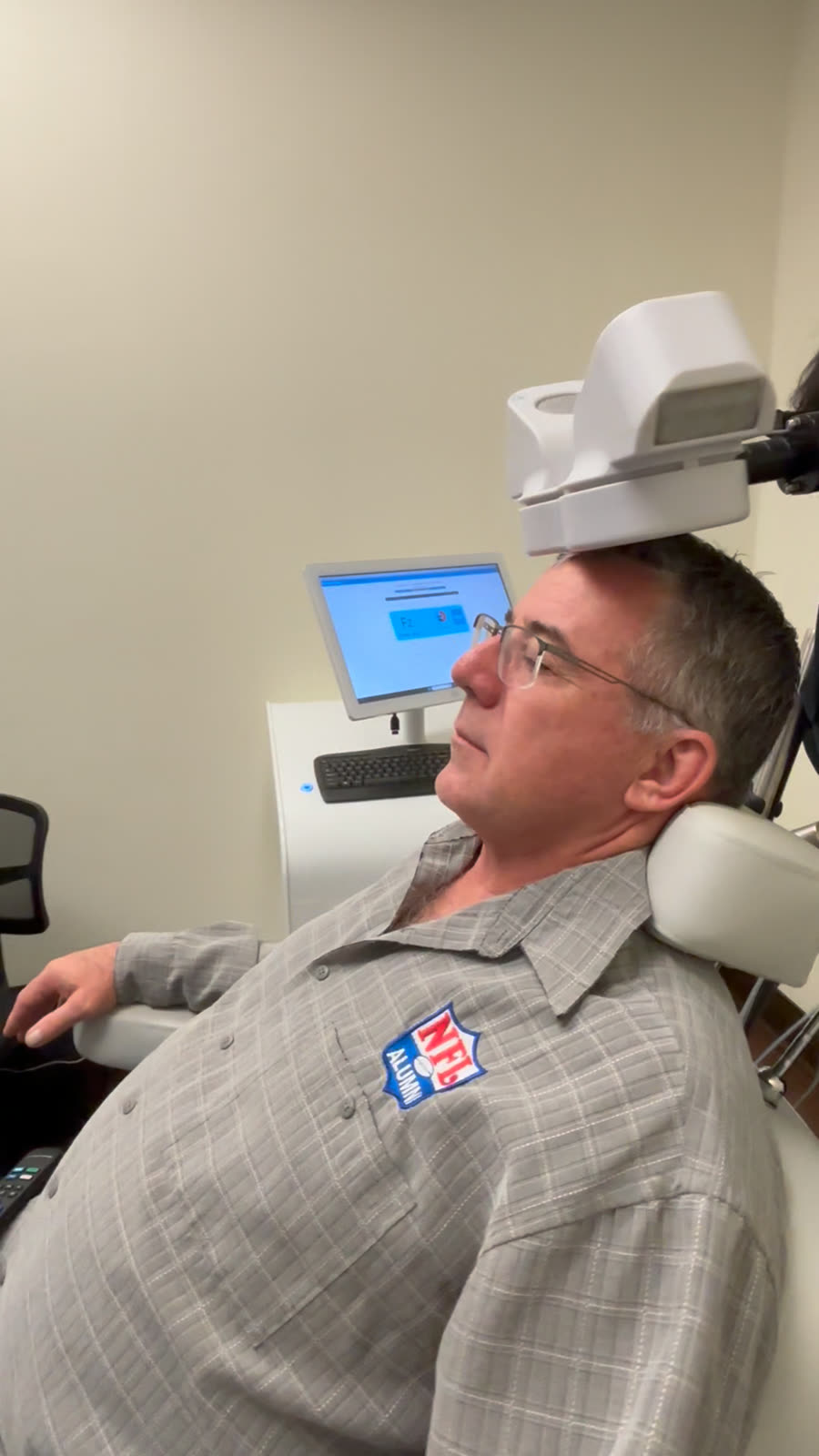 An NFL Alumni member receiving PrTMS treatment at MindSet, with brainwave readings on the monitor beside him